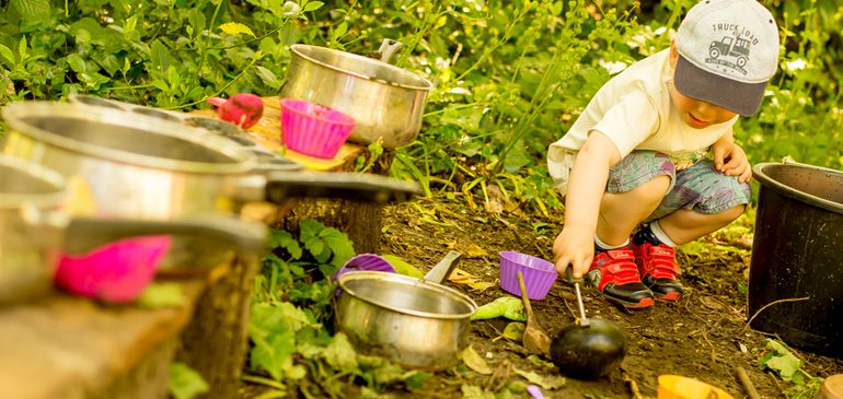 Little boy playing in the MERL mud kitchen in the sun