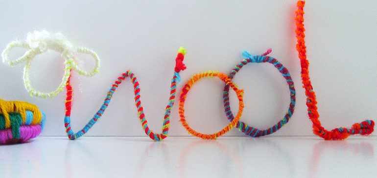 Craft of brightly coloured wool spelling out the word wool and a sheep's head