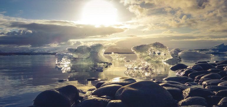 Landscape of water and ice caps with a setting sun