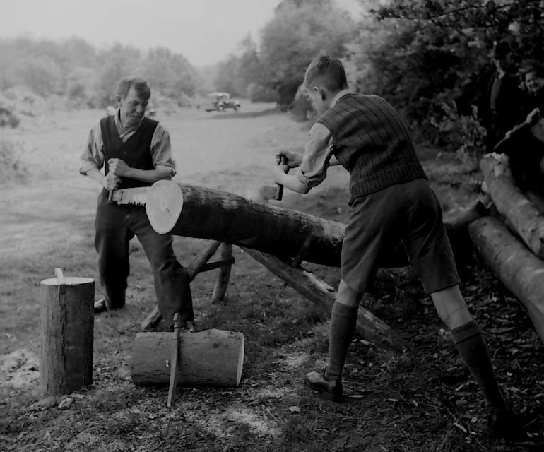Black and white photograph taken in the 1940s of a man and boy sawing a tree trunk.