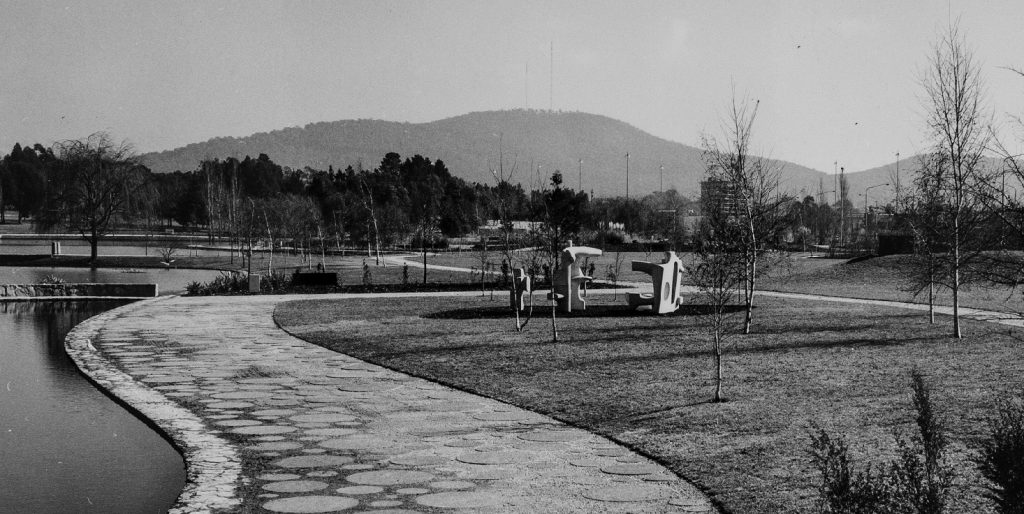 A photograph of Tolley's play sculpture, showing a lake and path with hills in the background.