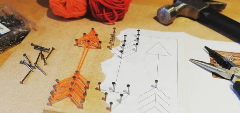 Board with string art of an orange arrow
