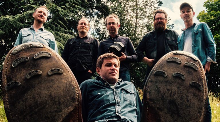 members of the servants ball band standing behind one member of the band on the ground with his boots with nails on soles for step dancing in the foreground