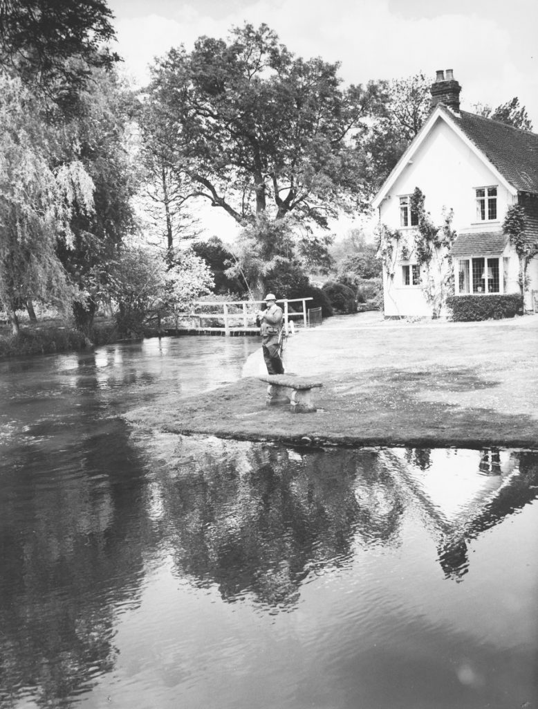 Black and white photograph of Jack Sheppard of Winchester playing a brown trout in the mill pool, Fulling Mill, River Itchen