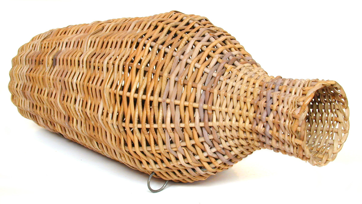 This eel trap, used for catching eels, was made by Stanley Bird of Great Yarmouth for the Museum. It is a Fenland eel trap made of cane, both round and split, with steel rings and galvanised wire. Because the pith has been removed from the cane, the trap is able to sink by itself without the need for weights. (MERL 63/606)