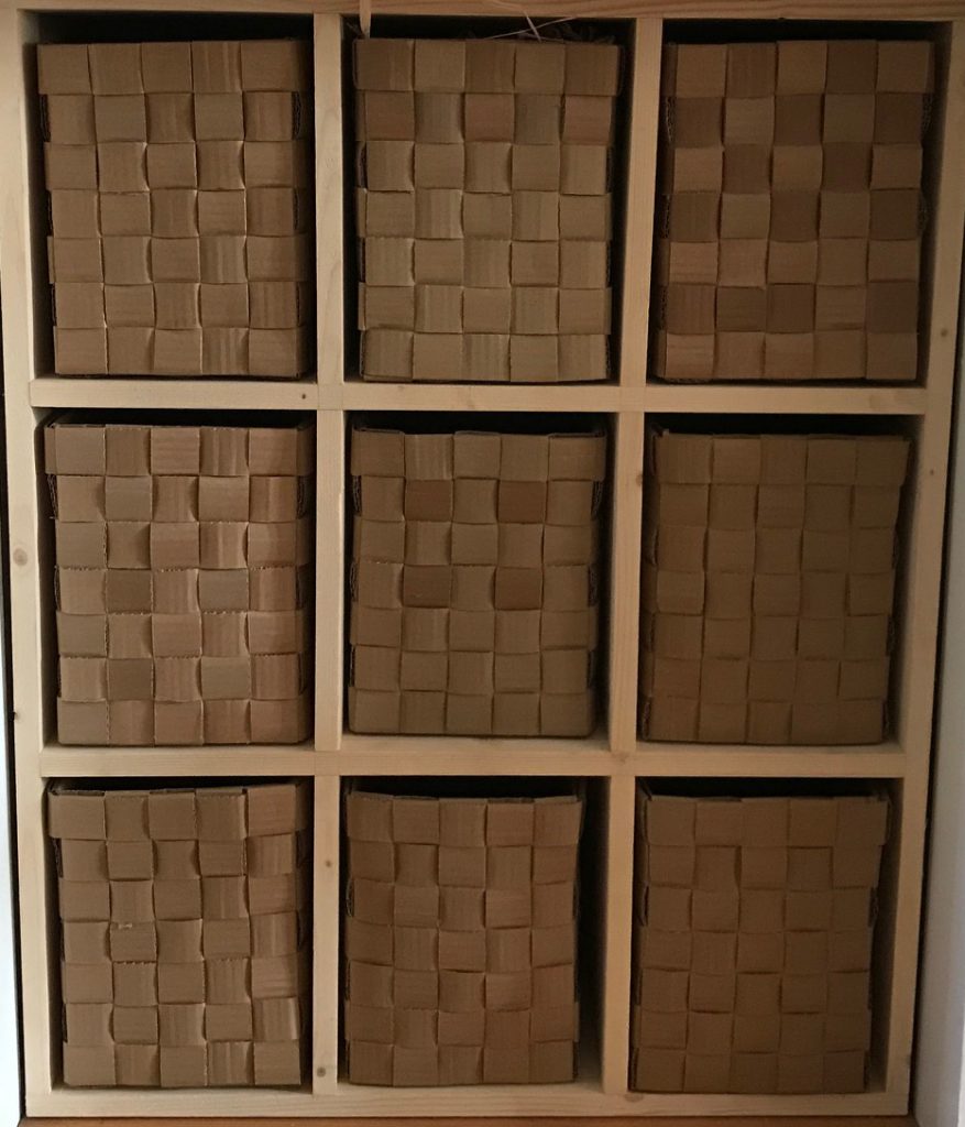 Nine baskets woven from strips of cardboard creating a chequerboard pattern