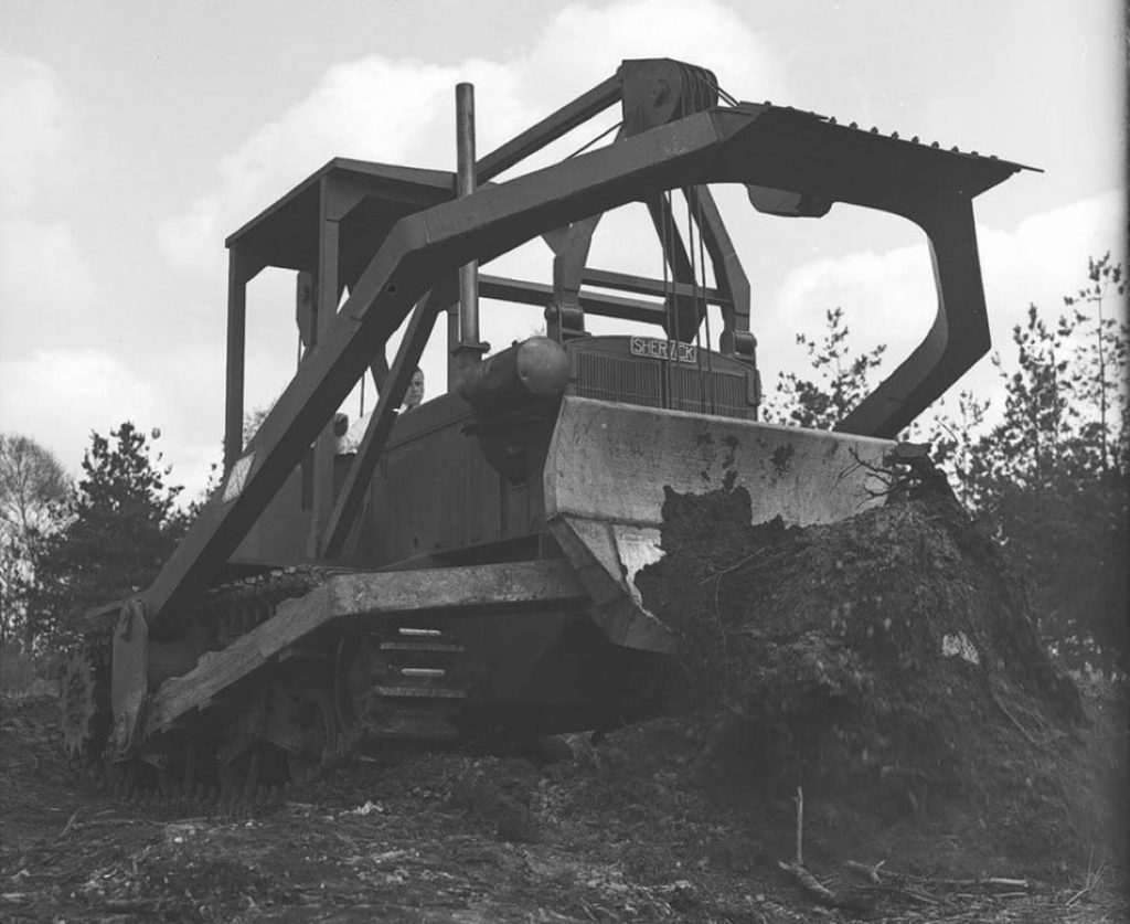 Black and white image of a repurposed tank serving as a crawler tractor.