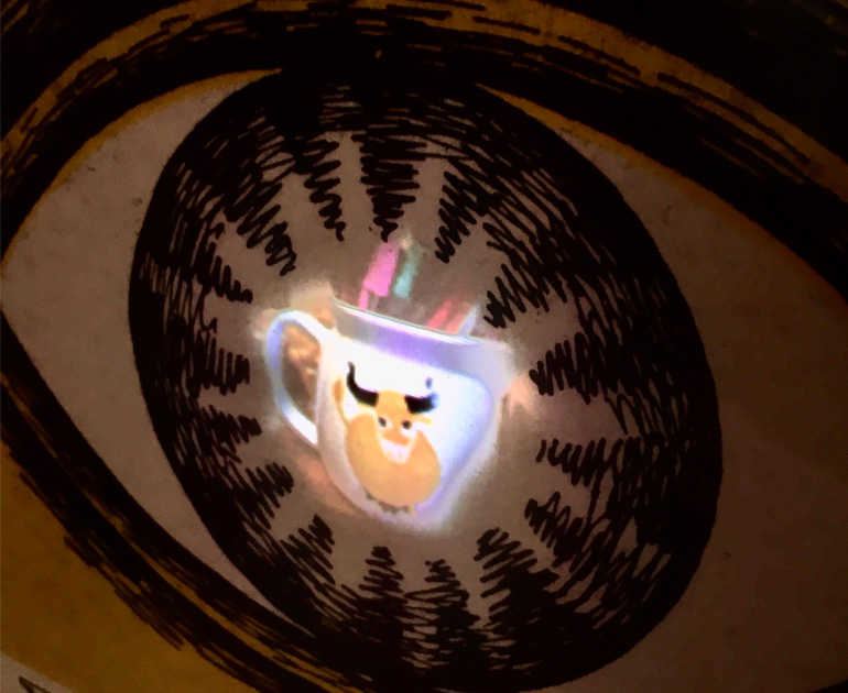 A bright image of a cartoon cow on a jug in the centre of a large drawing of a pupil of an eye