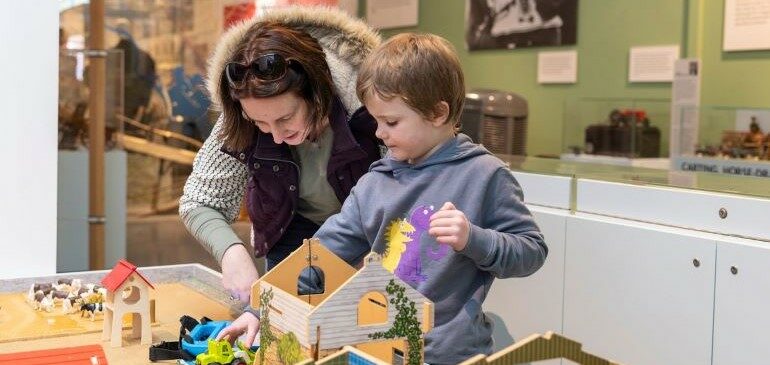 Family playing at the farm table in the Toys gallery at The MERL