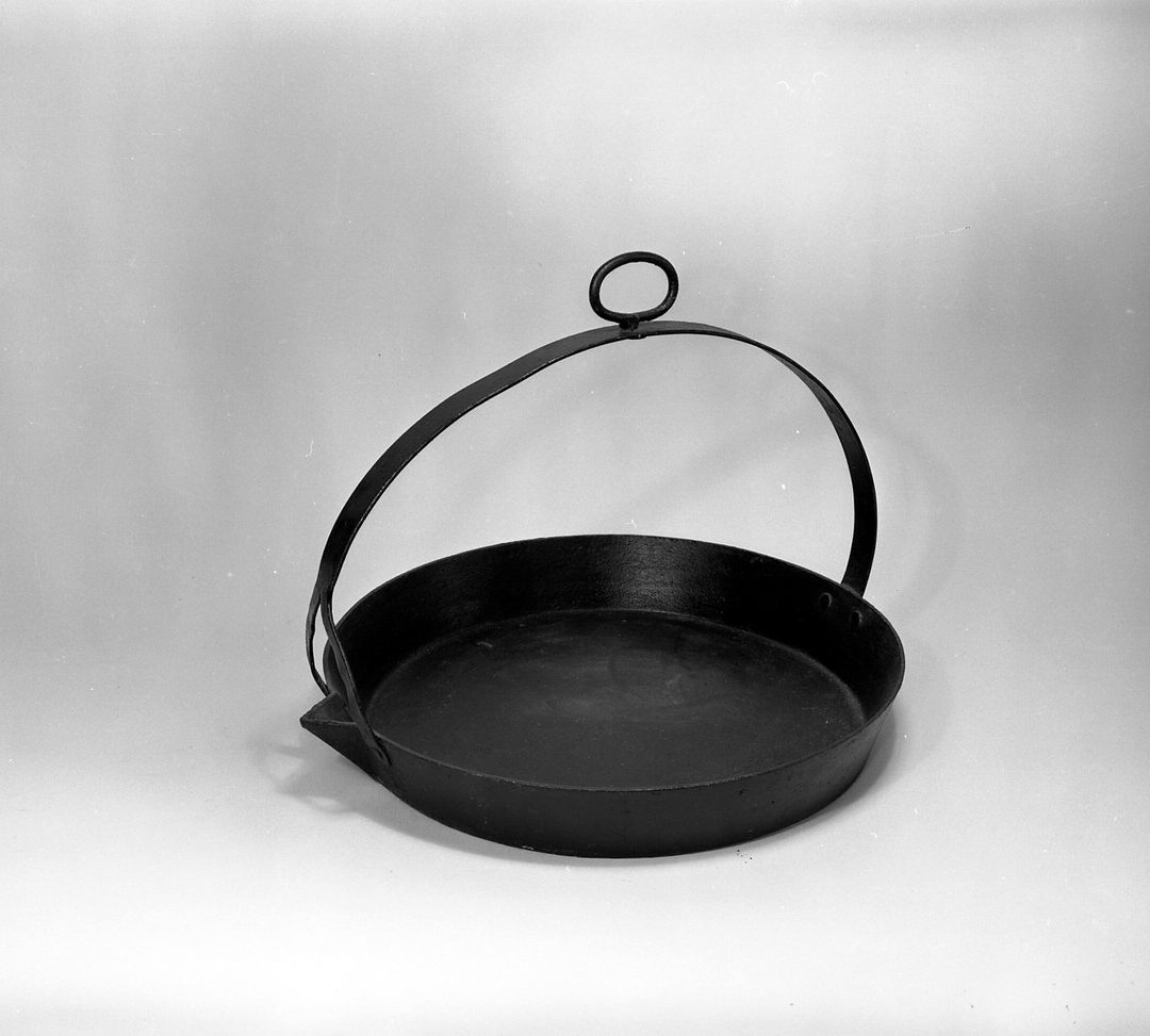 Frying pan (object name) The origins of this large, solid, iron pan are unknown. It was made to hang from a pothook over an open fire.