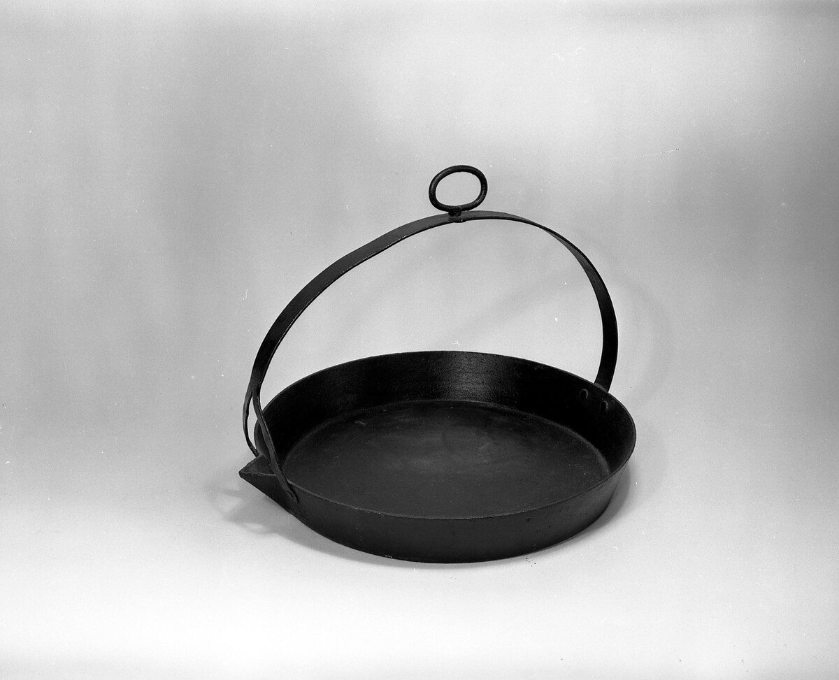 The origins of this large, solid, iron pan are unknown. It was made to hang from a pothook over an open fire.