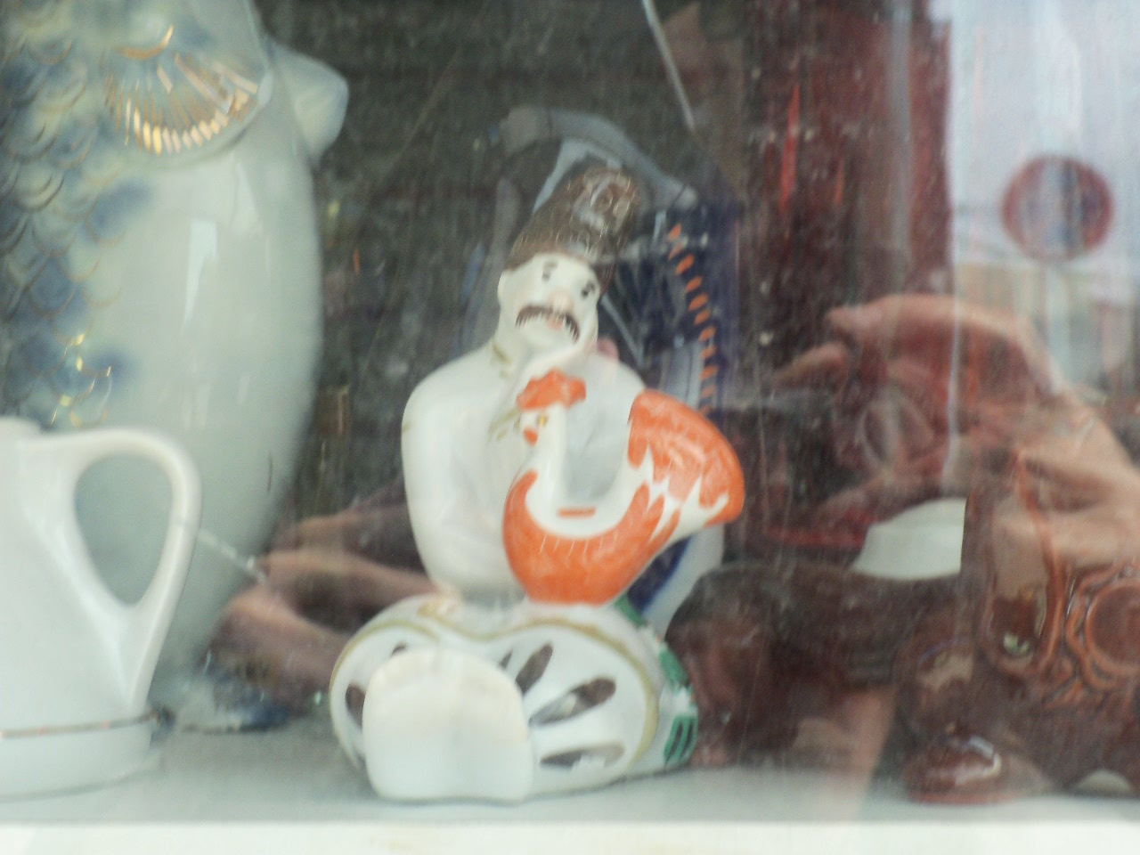 A figuring of a Ukrainian man. He sits with a red cockerel.