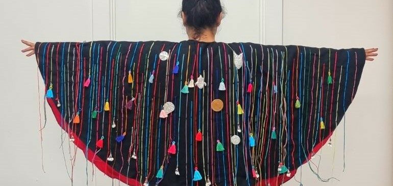 Model wearing a cape that is part of the Sew What exhibition