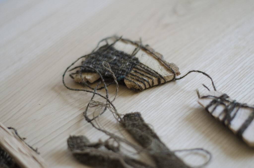 Detail showing threads of machine-wool bound to green ash on a table top surface.