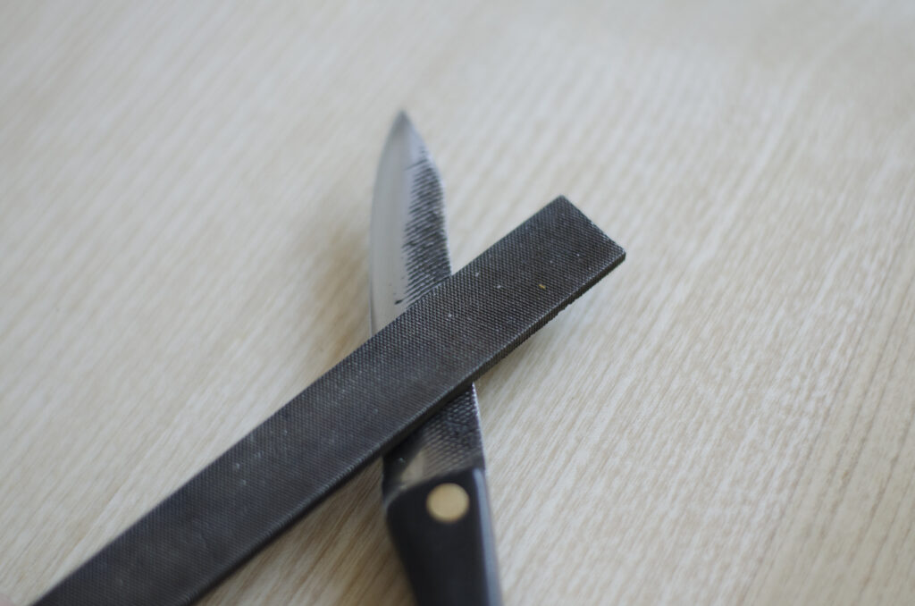 Detail of deconstructed file and handmade paring knife sitting on table top surface