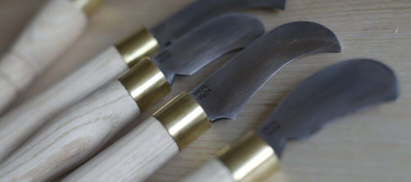 Detail showing domestic pruning knives inspired by billhooks sitting on a table top surface.
