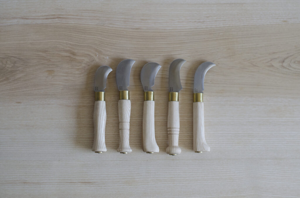 Domestic pruning knives inspired by billhooks sitting on a table top surface.