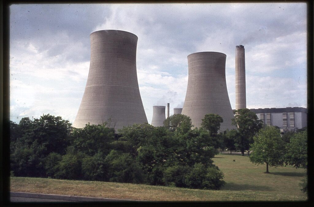 Colour slide of Didcot power station landscaping, showing trees and shrubs around the base of the several large concrete cooling towers, with other narrow tall chimneys dotted between.