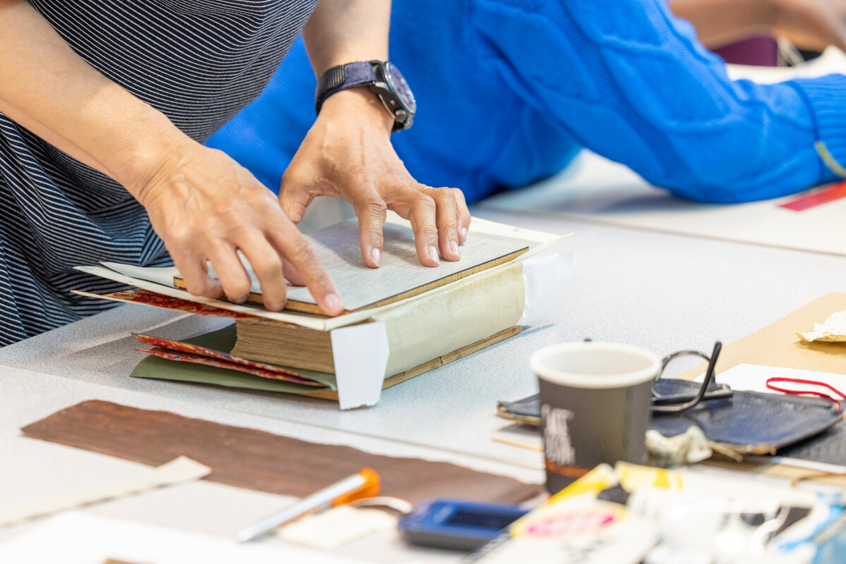 a close up photo of someone pressing down hard onto the back cover of a home made book as if to fix it in place