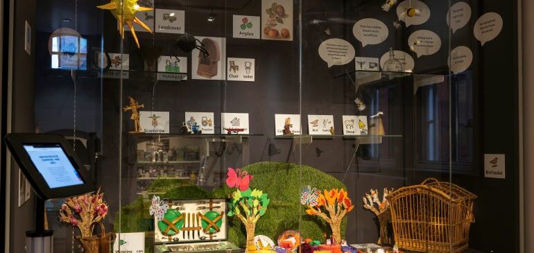 Display case containing museum objects, crafted picnic items and makaton symbols