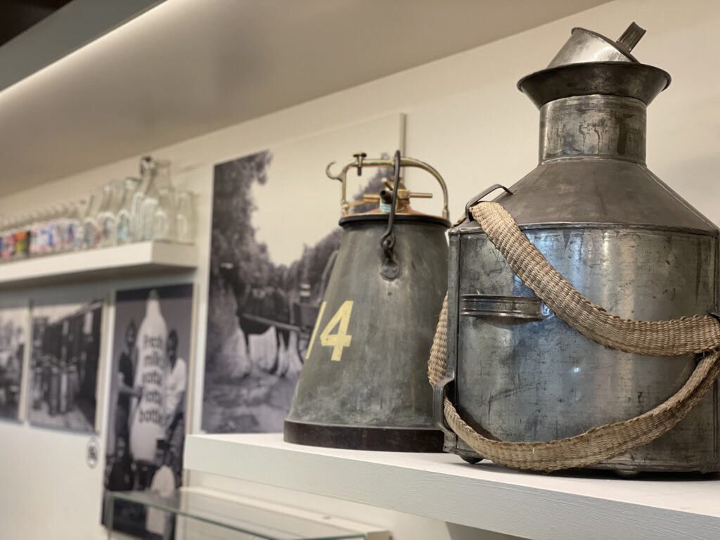 A dairying back canister and a portable milking machine with further dairy-related displays in the background