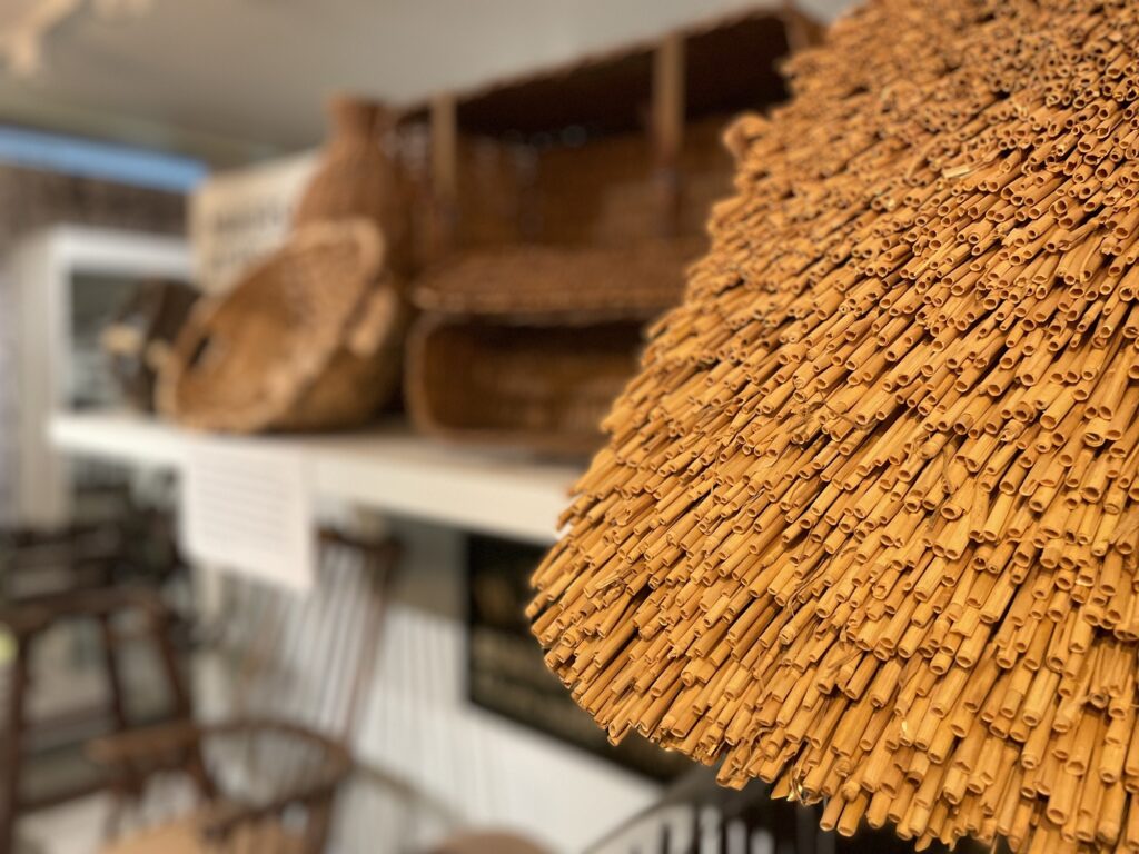 Thatch in focus in the foreground and heritage crafts objects in the background