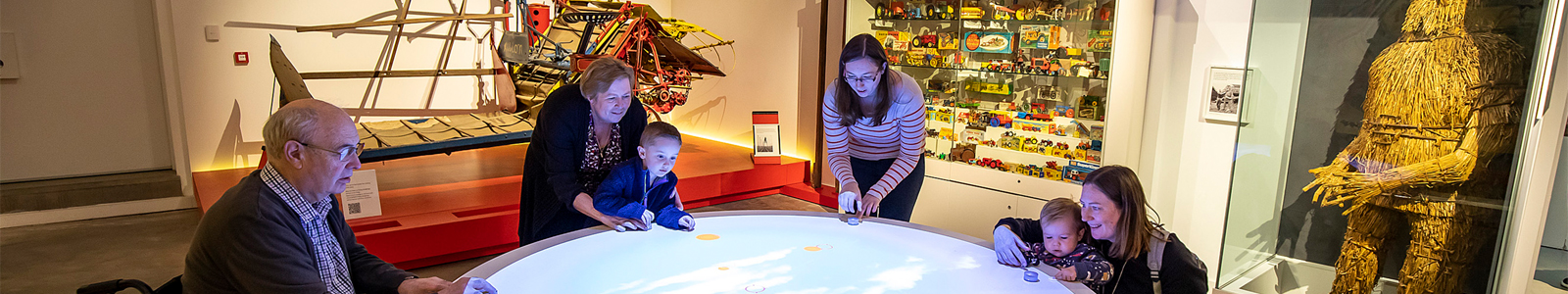 Adults and children playing at the interactive game table in the Our Country Lives gallery at The MERL