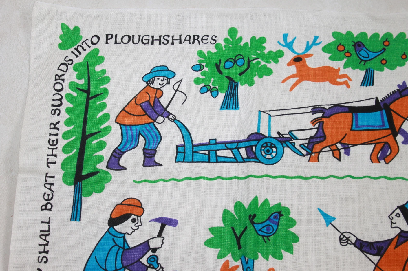 Detail showing of a vintage Oxfam tea towel bearing the biblical message of ‘Swords into Ploughshares’.