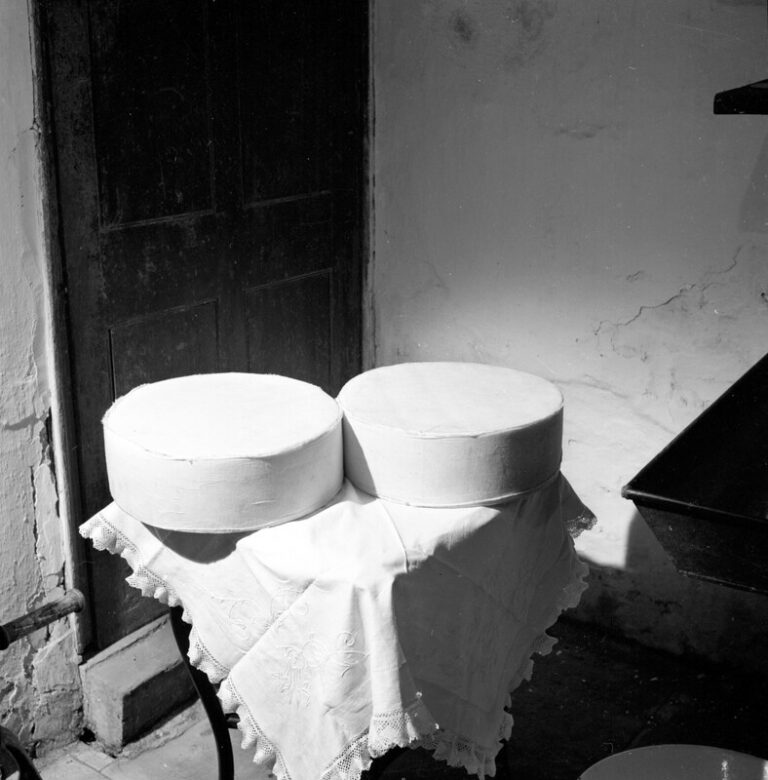 Two round cheeses, Double Gloucester, on a table with a white tablecloth