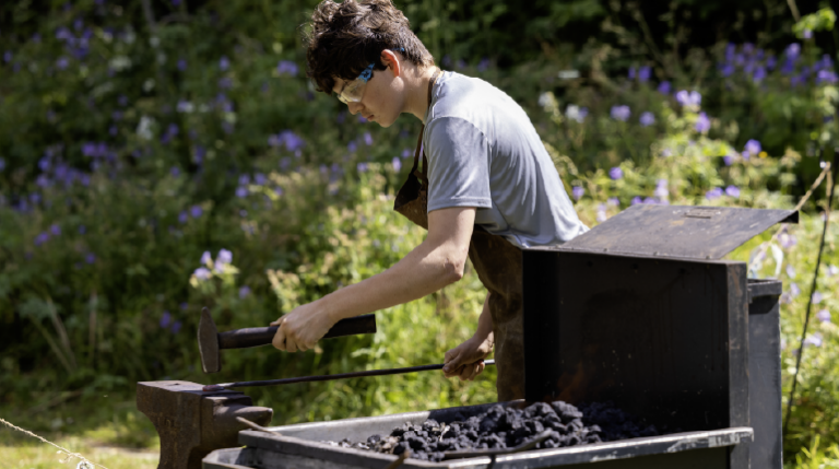 A boy blacksmithing at MERL