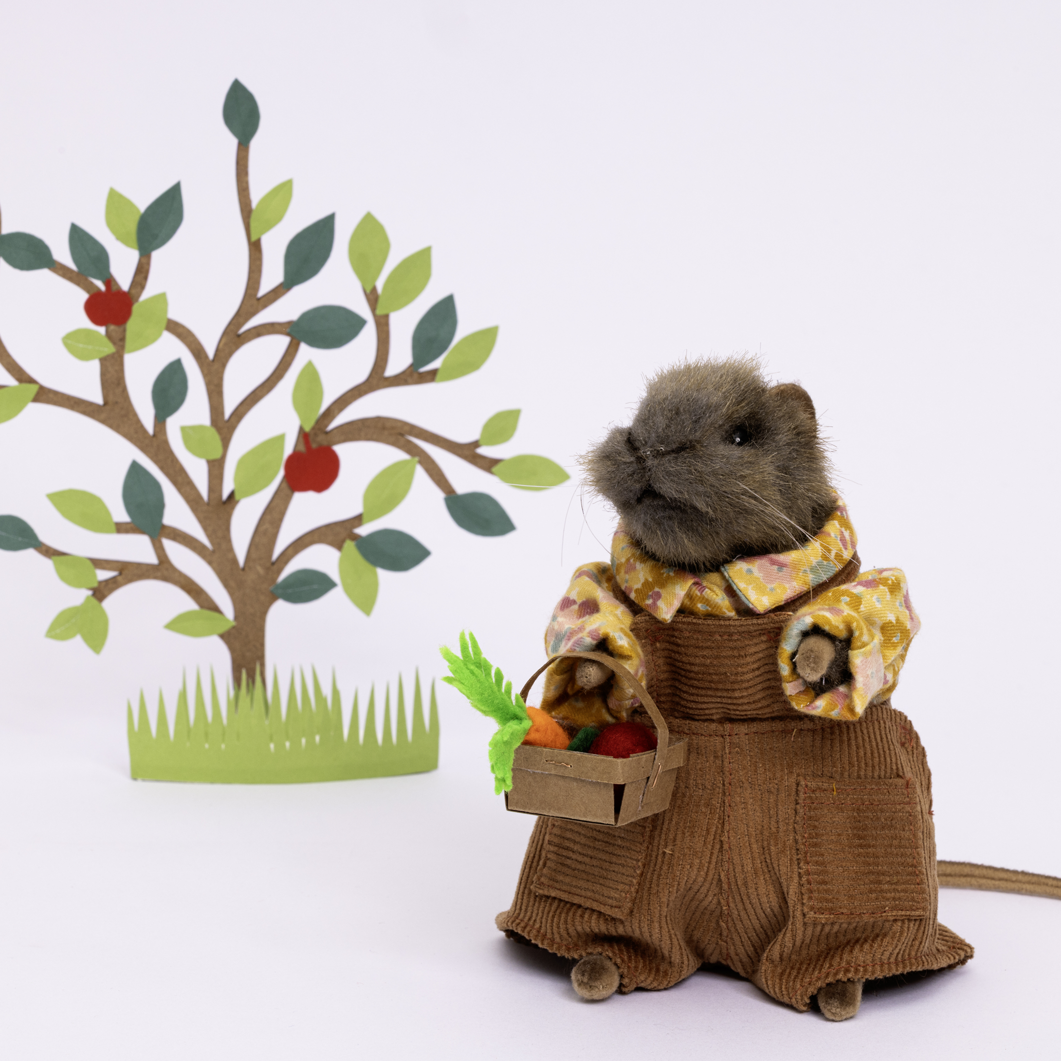 A rat wearing dungarees, holding fruit and veg