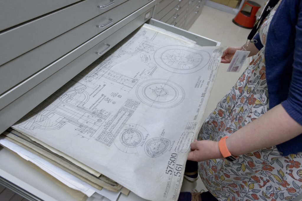An archivist looks at a drawing within a drawer