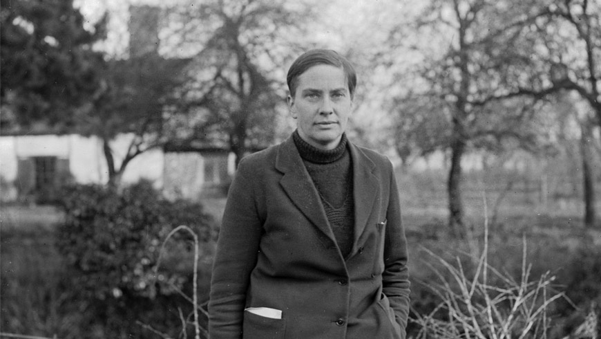 Lady Eve Balfour, in polo neck and blazer, standing in a garden