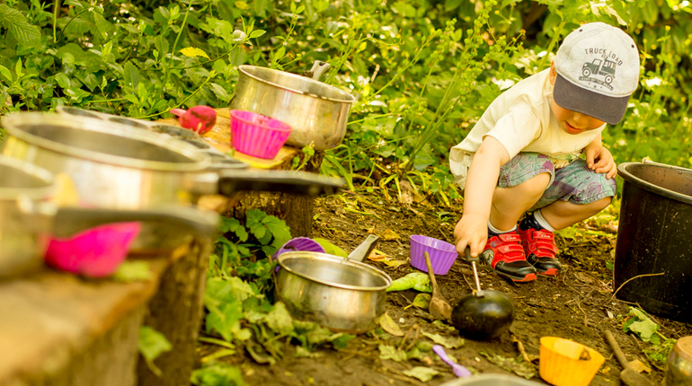 Little boy playing in the MERL mud kitchen in the sun