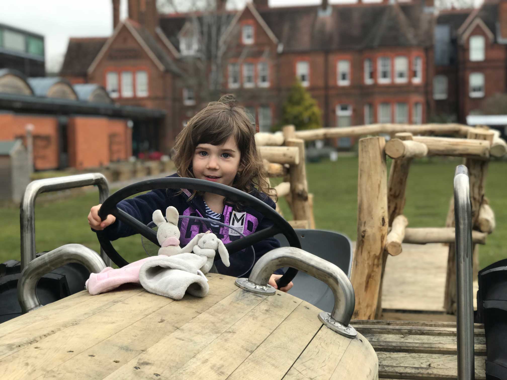 Child sitting on teh play tractor holding the steering wheel