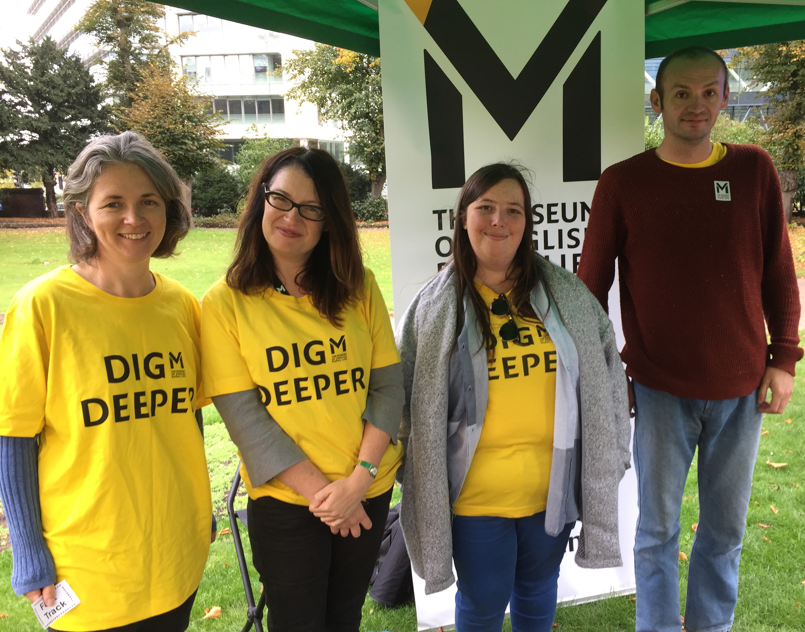 Members of MERL staff stand in front of a large banner with the MERL logo under a gazebo at an event