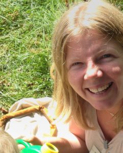 A close-up of Charlotte Allchin in the garden, smiling up at the camera