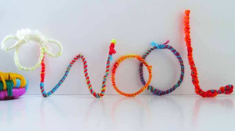 Craft of brightly coloured wool spelling out the word wool and a sheep's head
