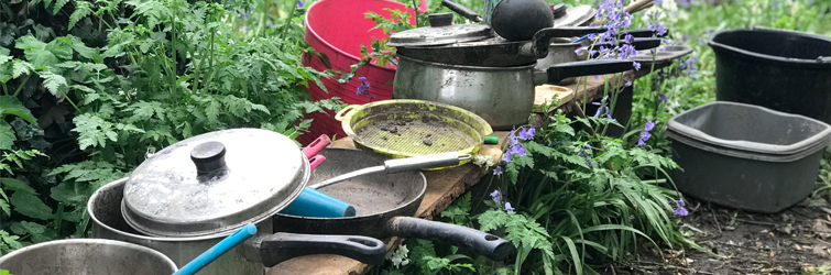 muddy pans piled on a bench in the garden