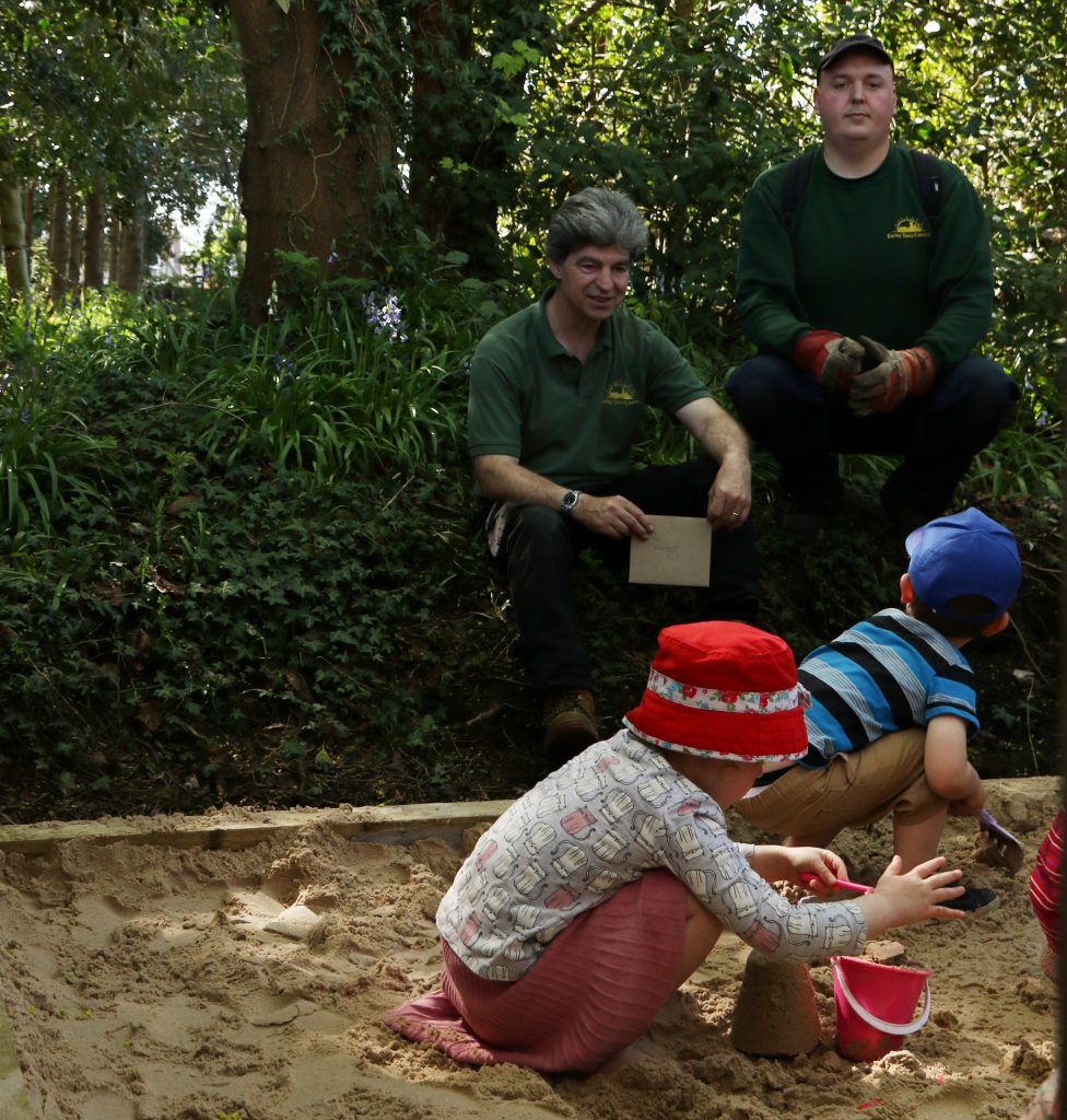 Two Rangers look on as toddlers try out the new sandpit in the MERL garden