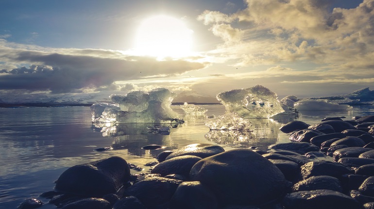 Landscape of water and ice caps with a setting sun