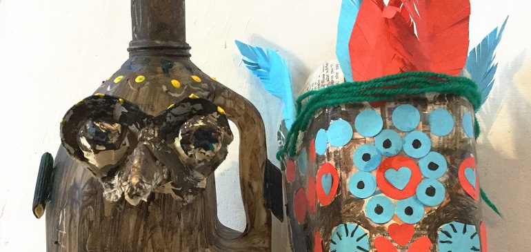A Melanesian mask (blue and red) and a grumpy medieval face jug made out of recycled materials.