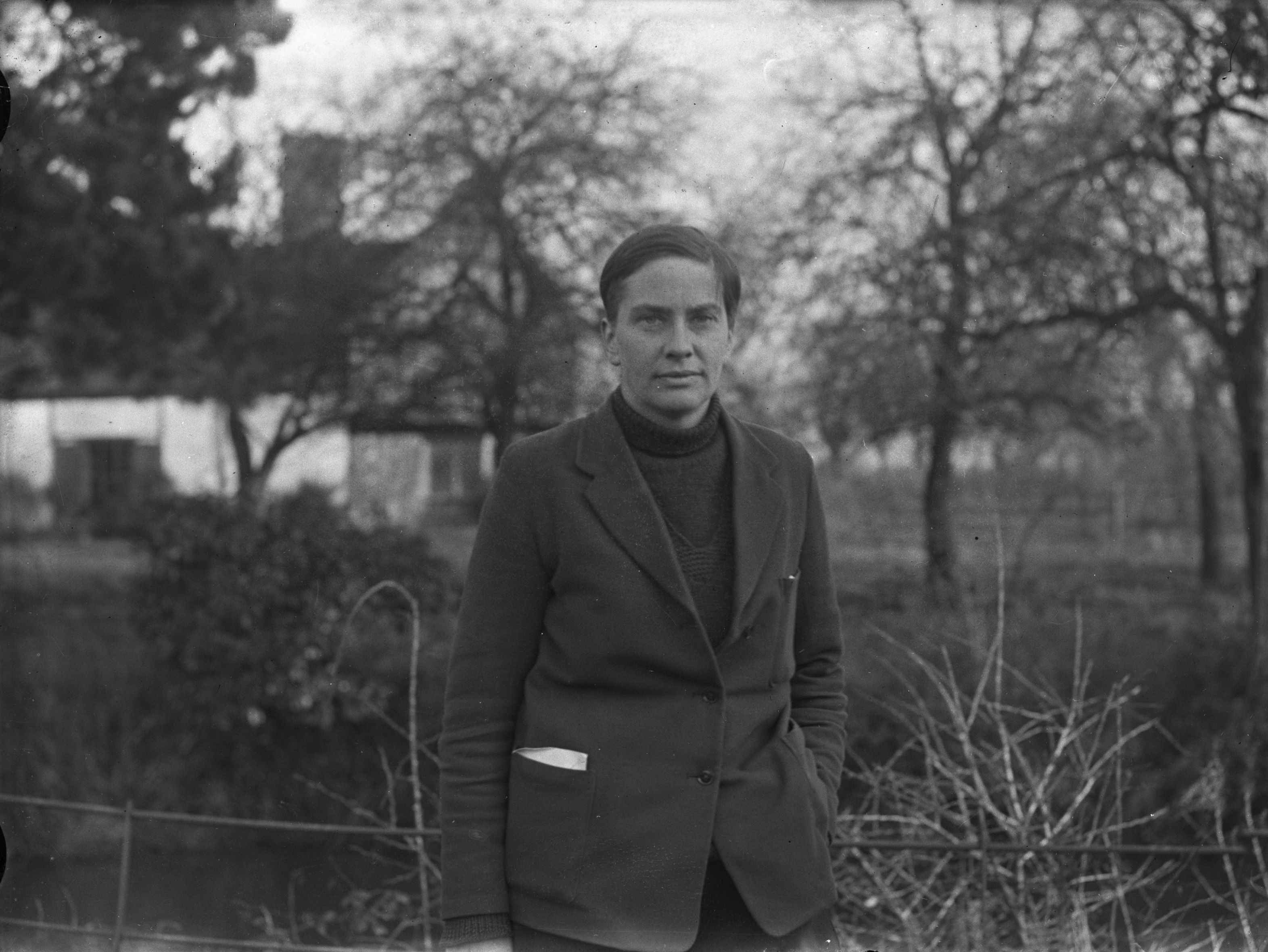 A black and white photograph of Lady Eve Balfour with trees and a house in the background