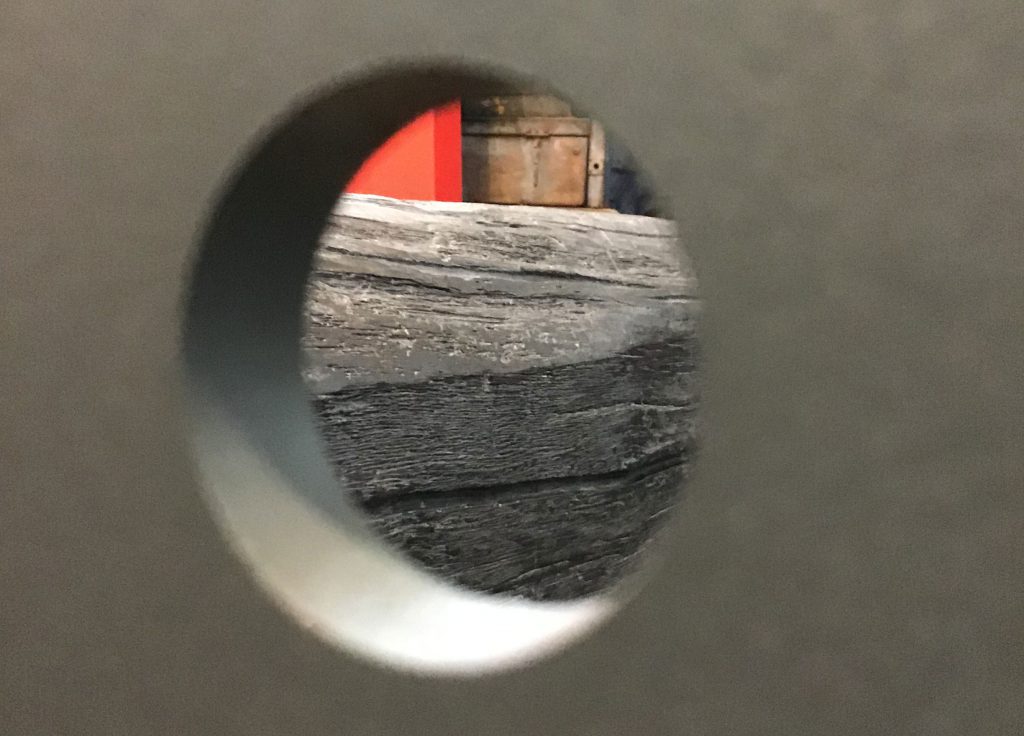 A view through a hole through to unidentifiable wooden structures featuring in the Reading International exhibition The Outside In