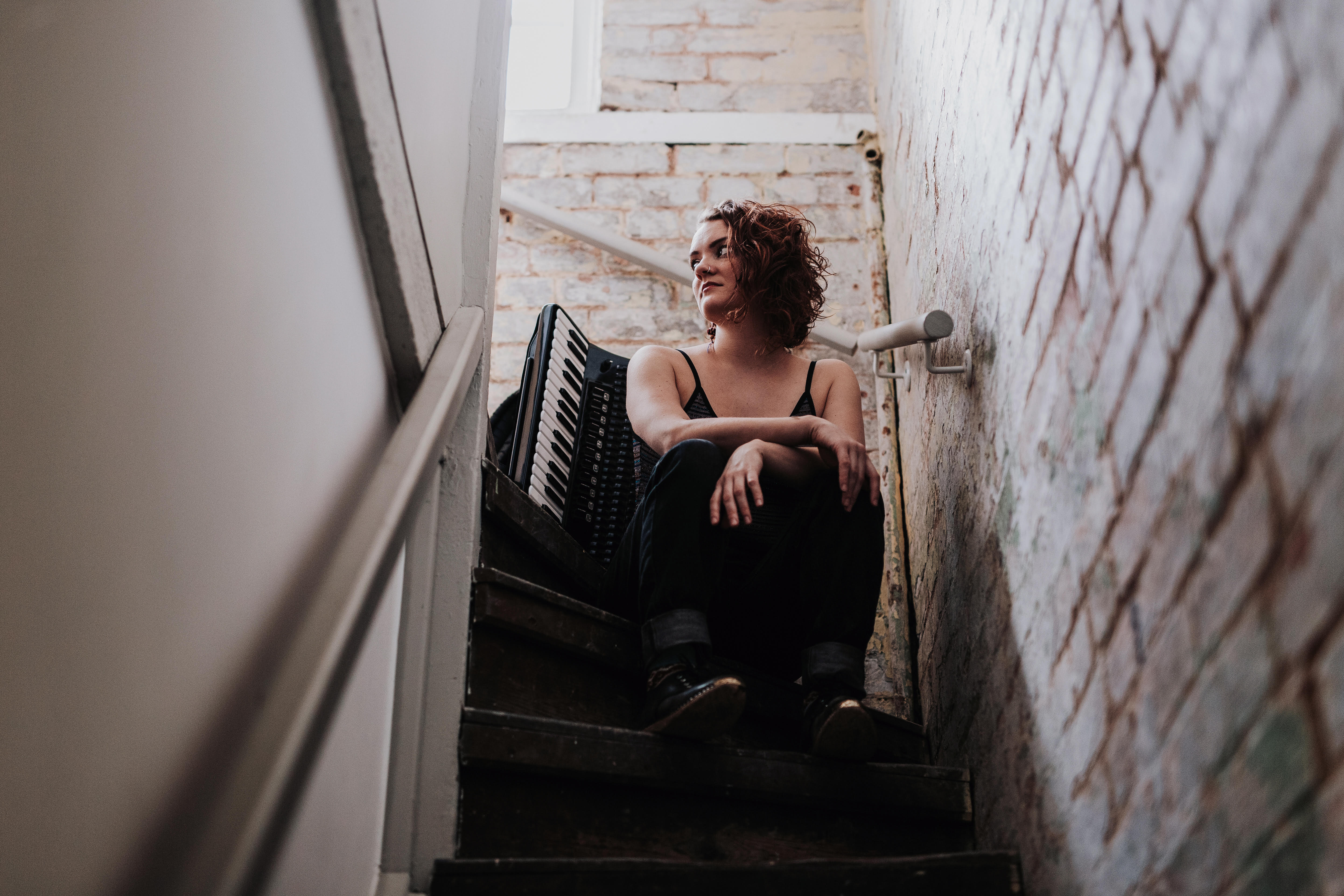 Hannah James sitting on some stairs next to her accordion 