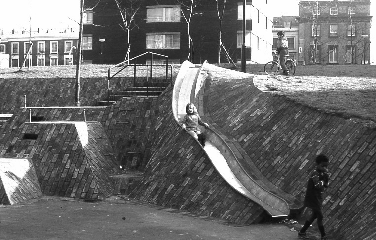 Black and white photograph of children playing around a slide at the Brunel Estate in 1974