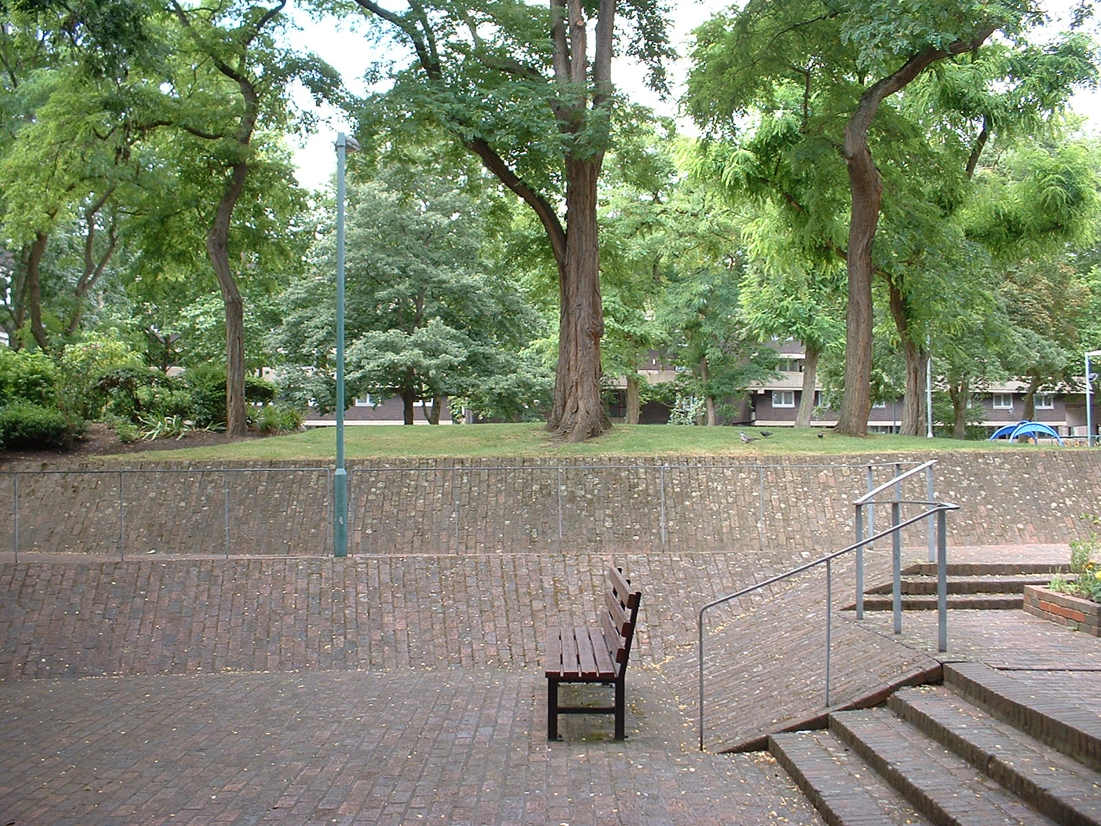 Sunken brick-paved square surrounded by large trees on the Brunel Estate in 2017