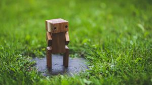 Small wooden robot figure standing in grass