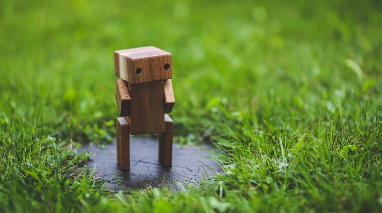 Small wooden robot figure standing in grass