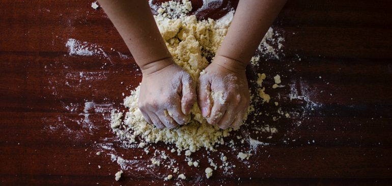 Hands kneading dough on a table